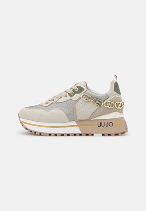 Beżowo-szary sneaker na sznurówki z grubą podeszwą, złotym łańcuszkiem, zielonymi zamszowymi akcentami i nadrukiem „LIU·JO” na boku.