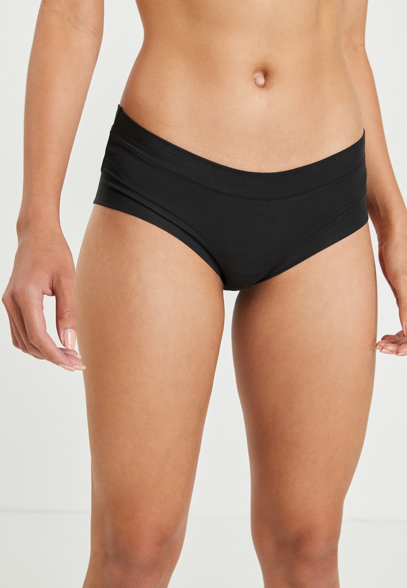 Parte inferior de bikini negra con una textura suave, que presenta una cinturilla ancha y cobertura media. Diseño simple sin patrones ni adornos.