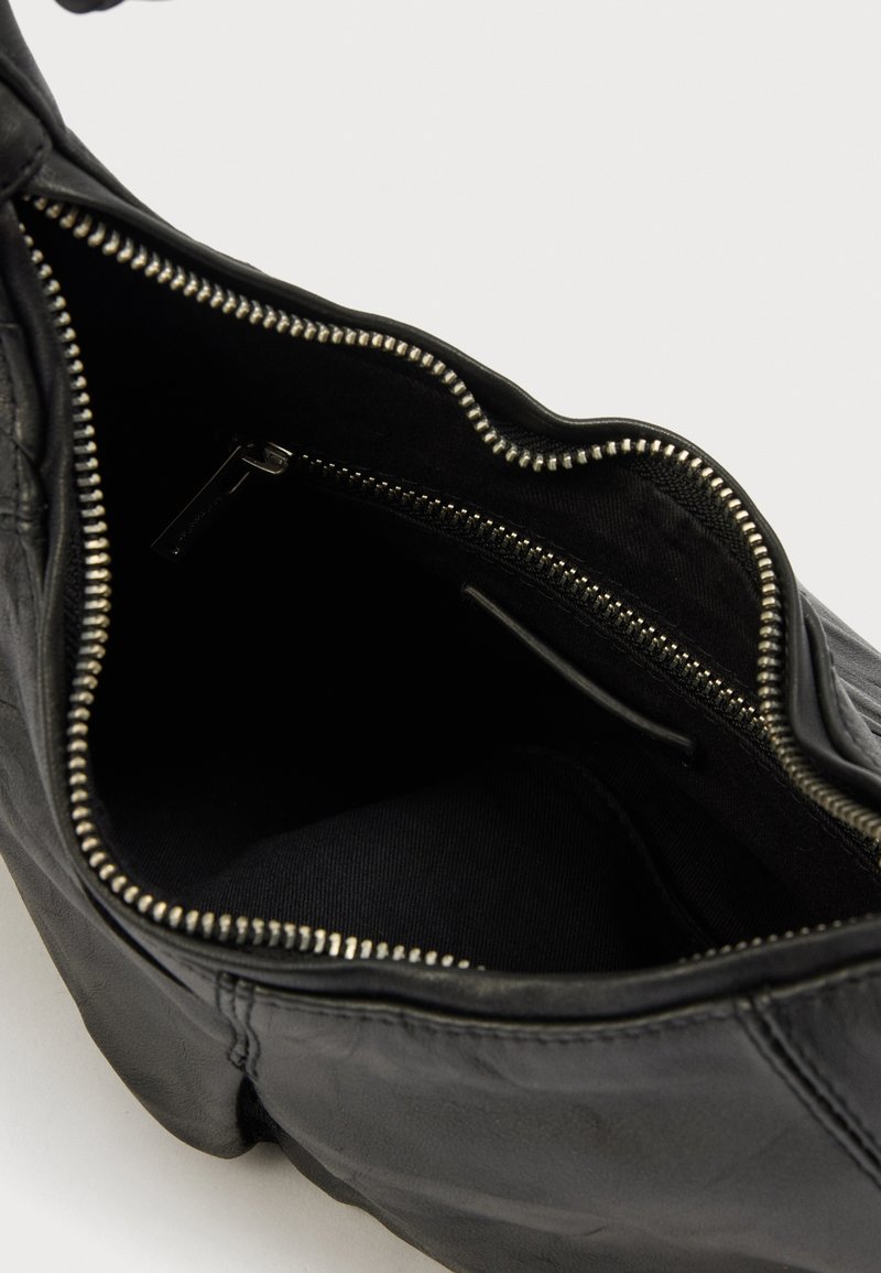 Zwarte leren handtas met een gestructureerde afwerking, voorzien van een ritssluiting en een ruime binnenkant gevoerd met zwarte stof.