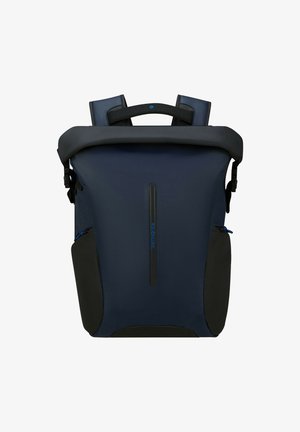 Navy blue roll-top backpack with black side pockets, padded shoulder straps, and a top handle, featuring a vertical zipper and logo on front.