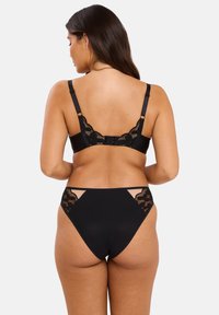 Soutien-gorge noir avec dentelle et culotte taille haute assortie. Tissu lisse avec des détails transparents à l'arrière et sur les côtés. Bretelles ajustables.