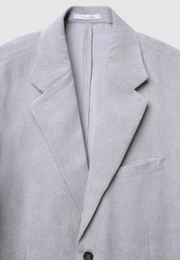 Hellgrauer Cord-Blazer mit Reverskragen, dezenten vertikalen Rippungen, Ein-Knopf-Verschluss und Brusttasche.