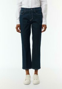 Dunkelblaue Jeans mit geradem Bein, Fünf-Taschen-Design und kontrastierenden Nähten, kombiniert mit weißen Sneakers.