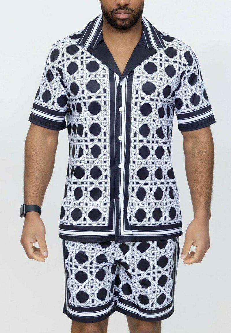 Ensemble composé d'une chemise à manches courtes et d'un short, présentant un motif géométrique bleu marine et blanc, avec une texture lisse et des détails de finition contrastés.