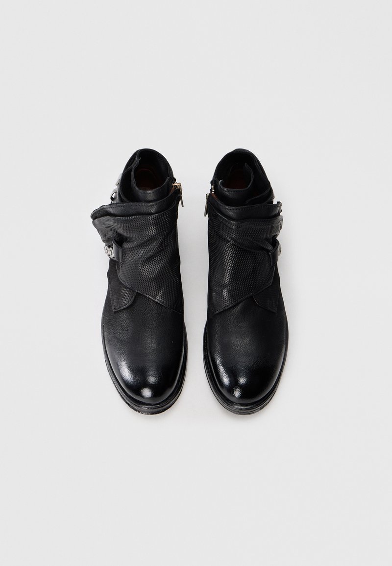 Par de botas de tobillo de cuero negro con puños texturizados y cremalleras laterales sobre un fondo blanco.