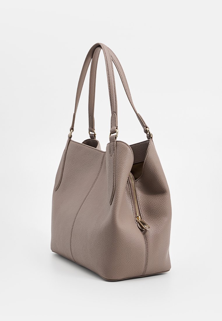 Beżowa skórzana torebka o teksturowanym wykończeniu, z dwoma ramiączkami, kieszenią na zamek i miękką, poduszkową formą.