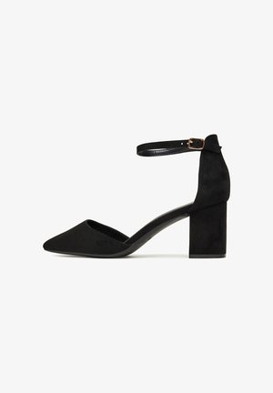 Schwarzer Wildlederpumps mit spitzer Kappe und Knöchelriemen. Blockabsatz und glatte Textur verleihen dem Gesamtbild eine elegante Optik.