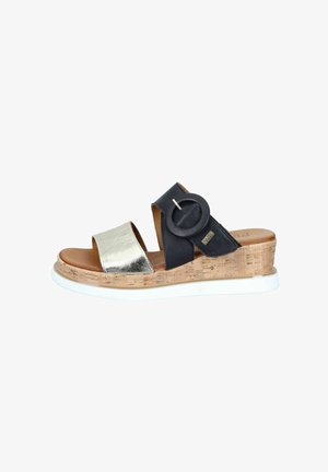 Wedge sandal with cork sole, metallic silver toe strap, black ankle strap with large round buckle, and white rubber outsole.