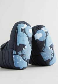Marineblå børnestøvler med polstret design, der har lyseblå dinosaur- og sky mønstre på sålerne og blødt stof på overdelen.