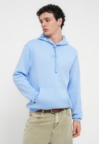 Φούτερ με κουκούλα σε ανοιχτό μπλε χρώμα κατασκευασμένο από μαλακό ύφασμα, με τσέπη μπροστά και ρυθμιζόμενο κορδόνι στην κουκούλα. Διαθέτει διακριτικό λογότυπο "GAP" στο στήθος. Κανονική γραμμή.