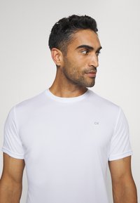 Witte crewneck t-shirt van gladde stof, met korte mouwen en een klein CK-logo in het grijs geborduurd op de borst.
