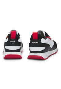 Black and white sneakers with red accents, featuring a padded collar, textured surface, and branding on the heel. Rubber sole with grip pattern.