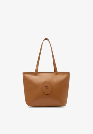 Hnědá kožená taška na rameno s dlouhými rukojetmi a oválnou nášivkou s logem uprostřed přední strany.