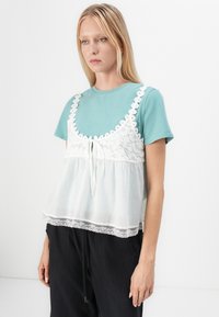 Lichtblauwe katoenen t-shirt gelaagd met een witte overlay met kant, met een strik aan de voorkant, korte mouwen en een relaxed fit.