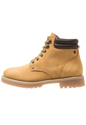 Bota de trabajo de cuero color canela con cordones, cuello acolchado de color marrón oscuro en el tobillo y suela gruesa de goma con tacos profundos, vista de lado.