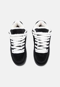 Black suede sneakers with white fluffy laces, rounded toe, padded collar, and smooth rubber outsole. Textured accents on the side.