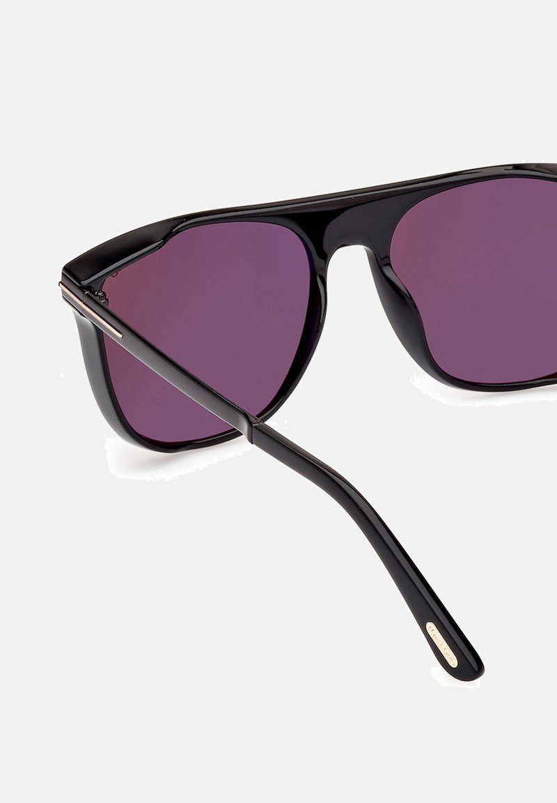 Occhiali da sole neri con lenti violacee sfumate, montatura elegante e dettagli argentati sulle tempie. Design leggero e moderno adatto a varie forme di viso.