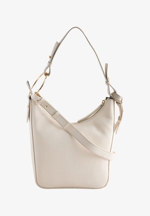 Cream leather bucket bag with adjustable strap, gold ring detail, and zipper closure on a white background.