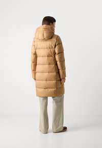 Langer, sandfarbener Puffer-Mantel mit Kapuze, mit horizontaler Steppung, seitlichen Taschen und einem leicht übergroßen Schnitt. Hergestellt aus glattem, gepolstertem Material.