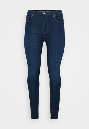 Dunkelblaue Jeans aus Denim mit einer taillierten Passform, mittelhohem Bund, fünf Taschen und kontrastierenden Nähten entlang der Nähte und Taschen.