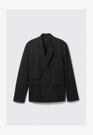 Črn blez s črtami, z izrezanimi reverji, enojnim gumbom in dvema spodnjima žepoma s poklopcem. Ima dolge rokave in strukturirano zasnovo.