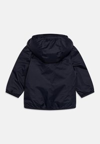 Giacca impermeabile blu navy con cappuccio, polsini elastici e una texture liscia e leggera. Presenta un design semplice e minimalista.