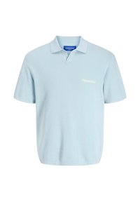 Lys blå strikket polo skjorte med V-hals, korte ærmer og blød tekstur. Har diskret broderi på brystet og en krave.