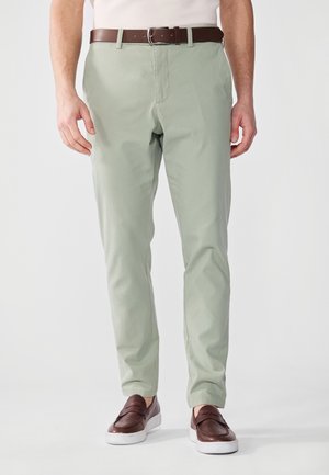 Lys grønne chinos med en glat texture og en lige pasform, parret med et brunt læderbælte og mørkebrune loafers.