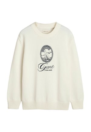 Krémový pletený svetr s kulatým výstřihem, ribbovanými manžetami a lemem, s námořnickým vyšívaným logem zobrazujícím plachetnici a název značky.