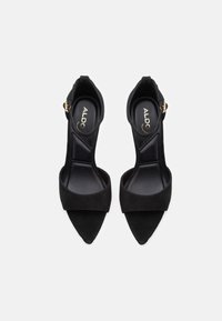 Zwarte suède sandalen met hak, een spitse neus, brede voorband, enkelbandje met gesp en een gladde, matte textuur.