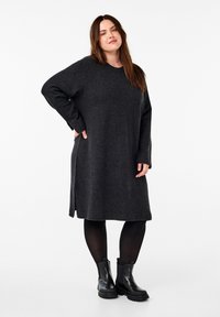 Mörkgrå långärmad klänning i mjukt tyg, med avslappnad passform, sidofickor och rund halsringning. Kombination med svarta ankle boots.