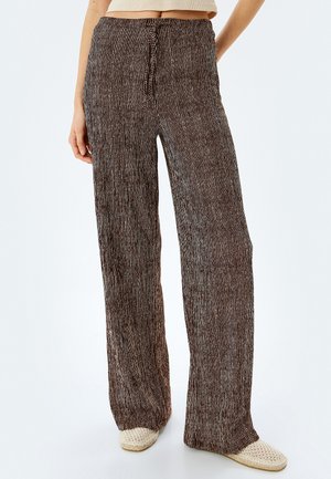 Pantalones de pierna ancha hechos de una tela marrón texturada con rayas blancas verticales. Cuenta con un cordón en la cintura y un ajuste desenfadado.