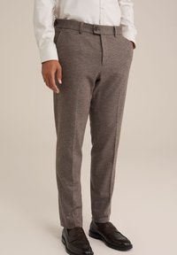 Bruine gestreepte broek met een rechte pasvorm, voorzien van een riem met knopen en zijzakken, gecombineerd met zwarte instappers.
