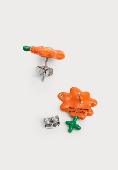 Narůžovělé náušnice ve tvaru květiny s zeleným stonkem, vyrobené z lesklého materiálu. Zahrnuje kovové komponenty ve stříbrném odstínu a značení značky na zadní straně.