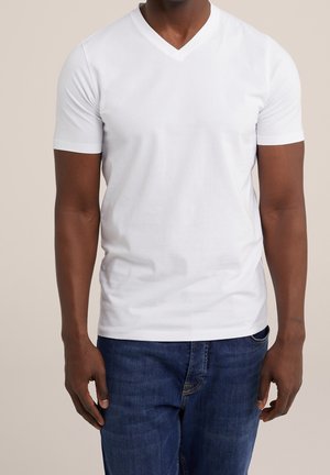 Weißes kurzärmeliges V-Ausschnitt-T-Shirt aus weicher Baumwolle, mit glatter Textur und figurbetontem Schnitt. Kombiniert mit blauen Jeans.