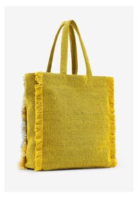 Żółta torba tote tkana z postrzępionymi brzegami, wykonana z teksturowanego materiału. Posiada podwójne uchwyty oraz otwartą, przestronną konstrukcję umożliwiającą łatwy dostęp.
