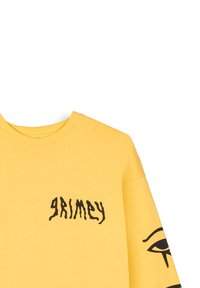 Camiseta de algodón amarilla con un logo negro de "GRIMEY" en el lado izquierdo del pecho y un gráfico de un ojo en la manga derecha. Diseño sencillo con cuello redondo.