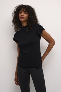 T-shirt noire à manches courtes dans un style ajusté, fabriquée en tissu lisse et extensible, associée à un jean skinny noir. Design simple sans motifs.