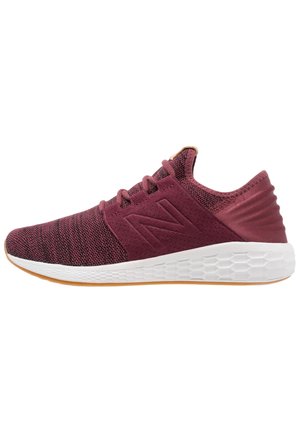 Chaussure de sport bordeaux avec une tige en maille texturée, une semelle en mousse hexagonale blanche et des lacets ton sur ton. Présente un logo proéminent sur le côté.