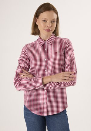 Red and white checkered long-sleeve shirt with a button-down collar, featuring a small logo on the chest and a curved hemline.