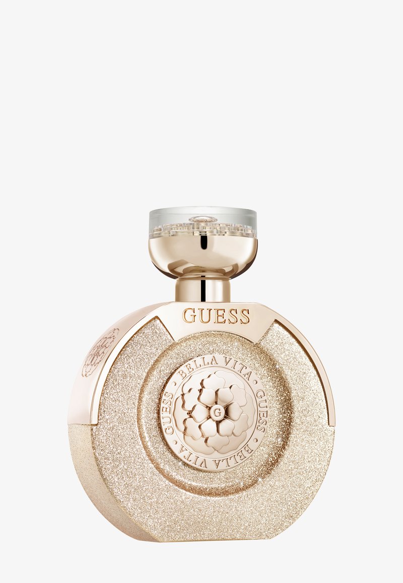 Runde Parfümflasche aus goldglitzerndem Material mit eingravierten Schriftzügen "GUESS" und "BELLA VITA", verschlossen mit einem glänzenden goldfarbenen Deckel mit klarem Einsatz.