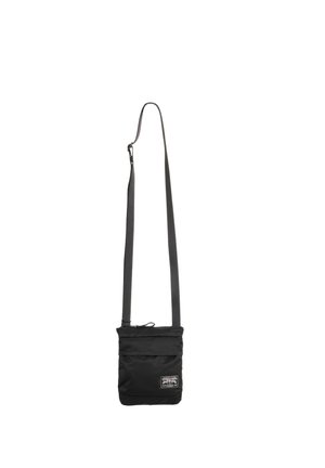 Sort crossbody taske med justerbar rem og lille hvid rektangulær logo-patch på den nederste forside.