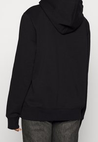 Black hooded sweatshirt with a relaxed fit, ribbed cuffs, and waistband. Soft cotton blend fabric, featuring a kangaroo pocket.
