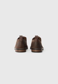 Brown leather shoes with a smooth finish, round toes, and back pull tabs, set on a dark brown sole. Logo visible on the sole edge.