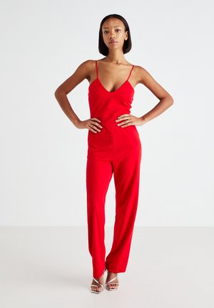 Rød jumpsuit med tynne stropper, v-hals, tettsittende liv og vide bukser. Glatt tekstur, minimalistisk design og en sømløs silhuett.