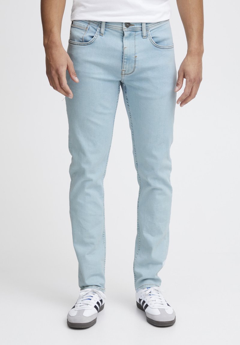 Ljust blå denimjeans med slim fit, femficksdesign och subtila sömnadsdetaljer, i kombination med vita träningsträn.