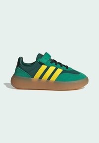 Gröna och gula sneakers med en överdel i mocka och syntetmaterial, en gummisula, tre ränder design och en kardborrebandstängning.