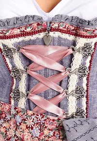 Le haut corset présente un tissu floral et rayé, un laçage en satin rose, une bordure en dentelle, des accessoires en métal et un pendentif en forme de cœur sur la fermeture éclair.