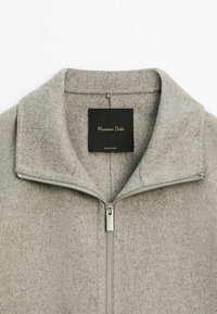 Szara kurtka zapinana na zamek z szerokim kołnierzem. Wykonana z miękkiego, teksturowanego materiału. Posiada srebrny zamek oraz czarną metkę z złotym napisem.