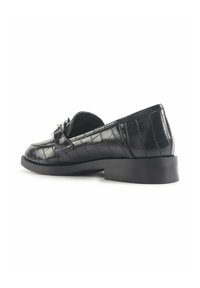 Mocassins en cuir noir avec une texture matelassée, bout rond et un petit talon bloc. Accessoire décoratif près de l'avant.